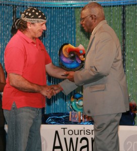 "Frothy" DeSilva accepts award from Oswald Williams, Sec. for Tourism and Transport award acceptance